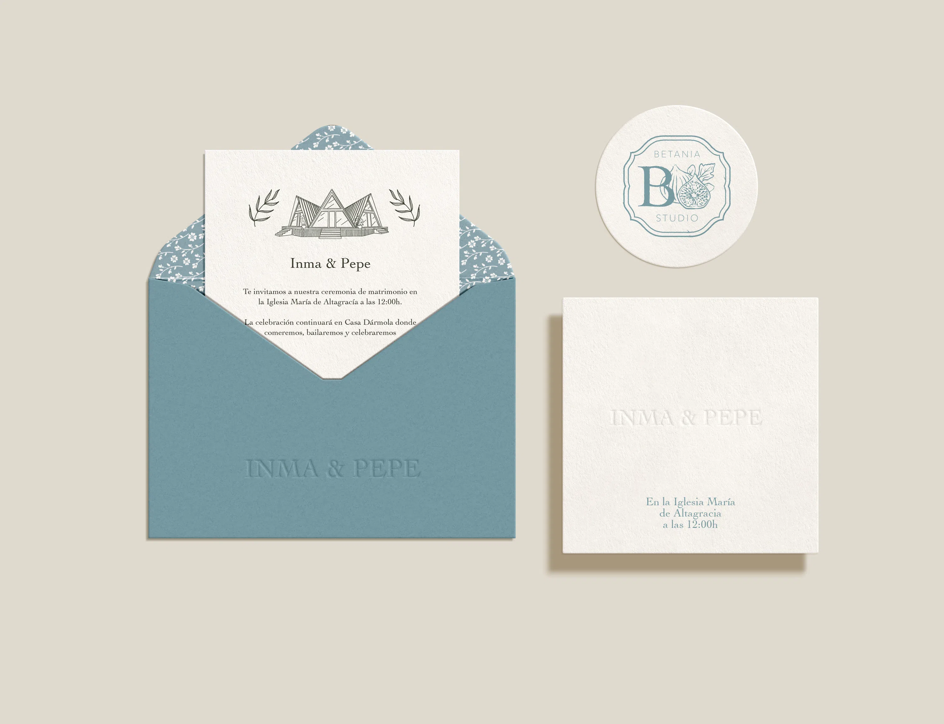 Invitación de boda personalizada en un sobre azul, con ilustración arquitectónica, tarjeta de ceremonia y sello circular.